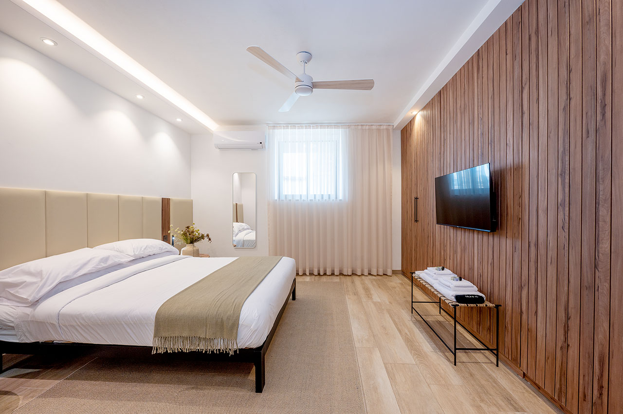 Main bedroom with wood slat wall and mounted TV
